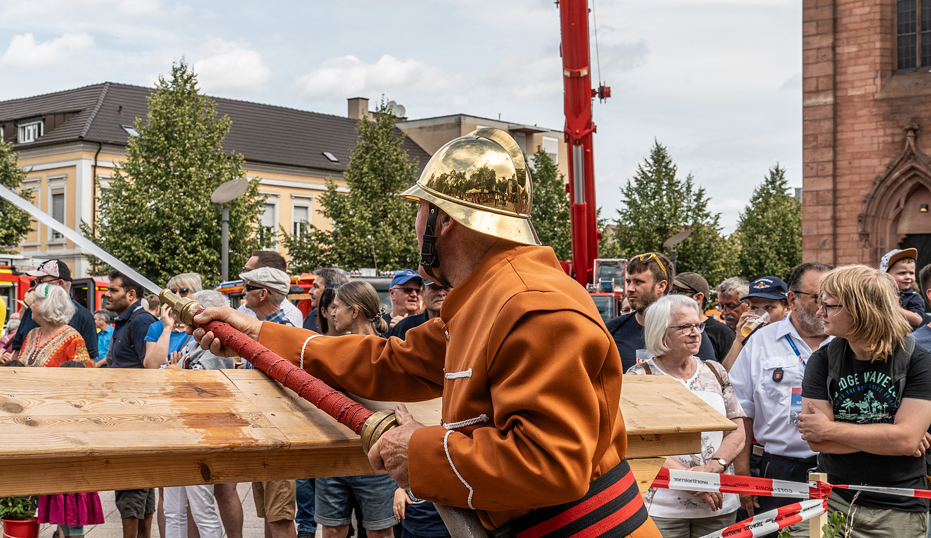 Ein Wehrmann bedient eine historische Handdruckspritze vor Publikum.